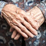 تصویر دستان یک پیرزن که روی هم قرار گرفته و چین و چروکهای دست را نشان میدهد.